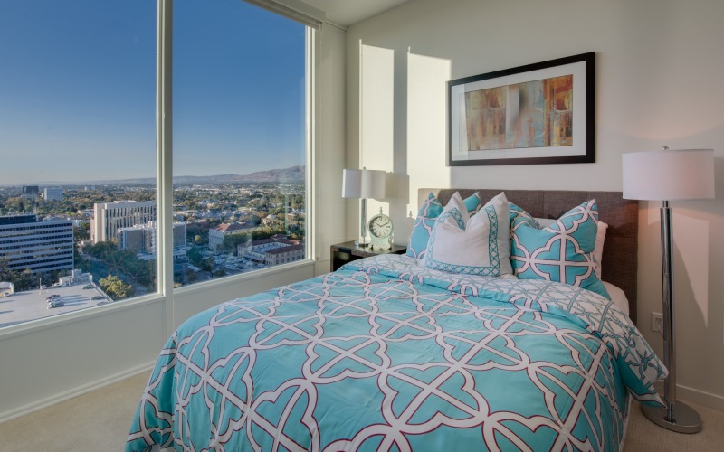 bedroom with a large window and a view of a city
